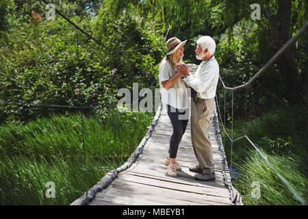 Romantische Active Senior Paar, Hände auf idyllischen Fußgängerbrücke Stockfoto