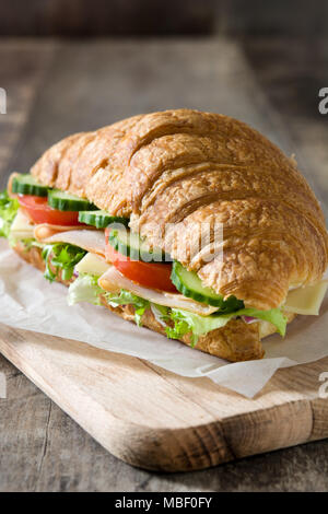 Croissant Sandwich mit Käse, Schinken und Gemüse auf hölzernen Tisch Stockfoto