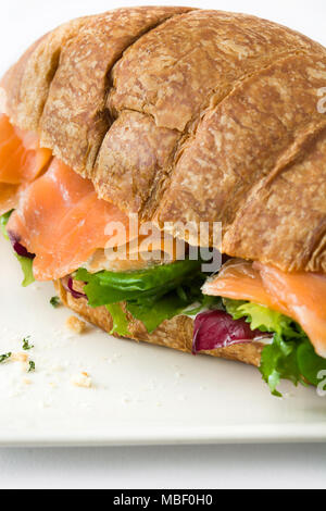 Croissant Sandwich mit Lachs und Gemüse auf weißem Hintergrund Stockfoto