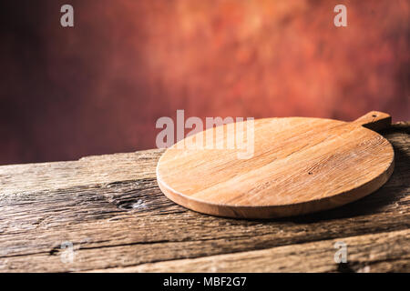 Leere Pizza Runde board alten Holztisch und Farbe verschwommenen Hintergrund. Stockfoto