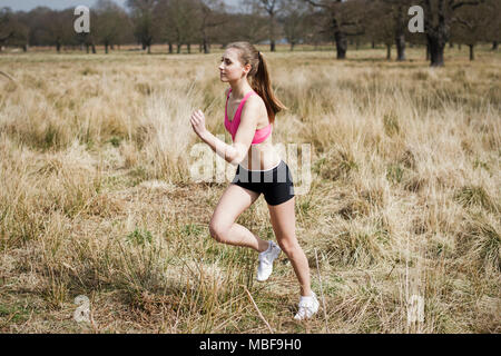 Junge Frau, die für die Übung im Freien in einem öffentlichen Park Stockfoto