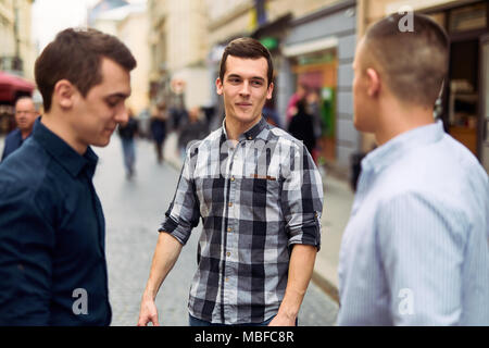 Drei Mann sprechen auf der Straße über Business Stockfoto