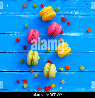 Bunte Kuchen von Mandeln Mehl mit Sahne macarons auf einem blauen Hintergrund, Macarons in der Mitte, Ansicht von oben Stockfoto