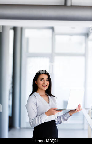 Erfolgreiche Frau staning in Amt, Laptop in Ihren Händen Stockfoto