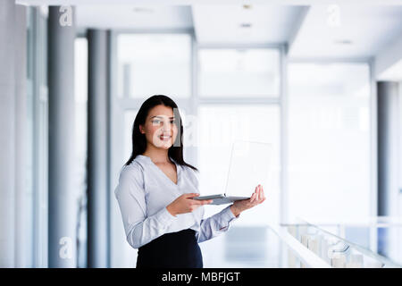 Erfolgreiche Frau staning in Amt, Laptop in Ihren Händen Stockfoto