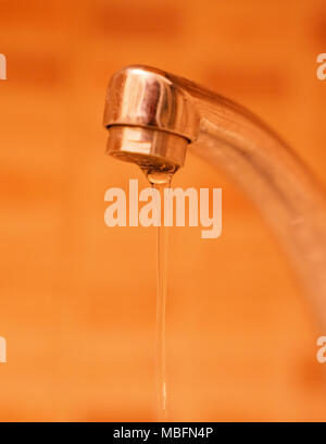 Wasser aus der orange Hintergrund tippen, Wasser sparen! Stockfoto
