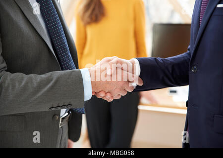 7/8 Schuß von zwei Unternehmer tragen Anzug und die Hände schütteln. Stockfoto