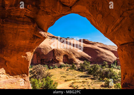 Felsformation und roten Klippen umrahmt durch einen Bogen im Monument Valley Navajo Tribal Park an einem sonnigen Tag des Sommers, Arizona Stockfoto