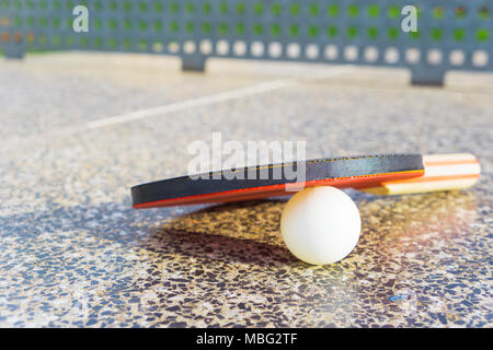 Nahaufnahme eines Ping-pong Paddle mit Tisch-tennis weiße Kugel auf einem Tisch-tennis Tisch aus Stein mit kopieren. Sport und Freizeit Konzept Stockfoto