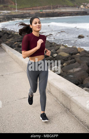 Sportliche Brünette, die auf der Promenade in Grey Strumpfhosen kastanienbraunen, Hemd und schwarze Turnschuhe Stockfoto