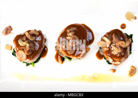 Flach Schuß von drei Kalbsfilet Medaillons mit Weißweinsauce und gekochte Kastanien auf Spinat treibt Stockfoto