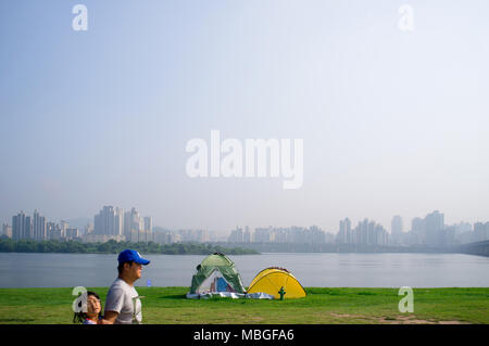 Ein Vater und eine Tochter Spaziergang, vorbei an zwei Zelten am Ufer des Flusses Han, Seoul, Südkorea. Stockfoto