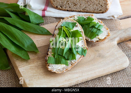Zwei Scheiben Sauerteig Brot mit Butter und Bärlauch Blätter Stockfoto