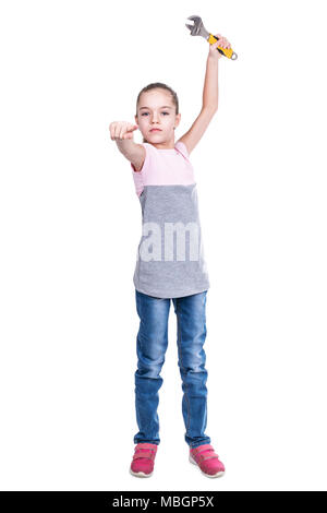 Junge Mädchen mit einem verstellbaren Schraubenschlüssel in der Hand Punkte Finger nach vorne an der Kamera auf einem weißen Hintergrund isoliert Stockfoto