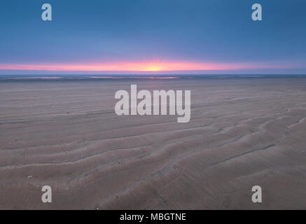 Wellen im Sand Greatstone Strand an der Küste von Kent bei Sonnenaufgang. Stockfoto