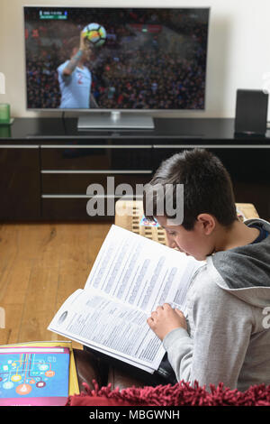 UK-Schüler, 10 Jahre alt und versuchte, zu studieren, während Fußball spielt auf TV Stockfoto