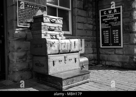 Monochromes 1940er-Jahre-Kriegsgepäck, Vintage-Gepäck. Gestapelte Koffer und altmodischer Kofferraum auf dem Bahnsteig des historischen Bahnhofs, Severn Valley Railway, Großbritannien. Stockfoto