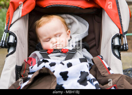 Ein 10 Monate altes Baby schlafend in seinem Stroller. Stockfoto