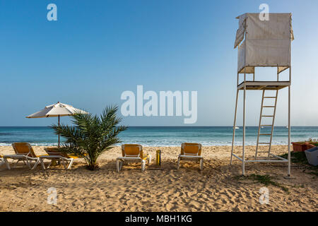 Sonnenliegen und Sonnenschirm neben Rettungsschwimmer stehen am Strand von Santa Maria, Sal, Kap Verde, Cabo Verde Stockfoto