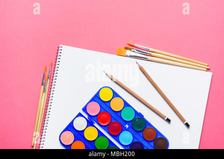 Palette mit Reihen von bunten Aquarellfarben Bürsten Bleistifte Skizzenbuch auf Rosa Hintergrund. Arts School Klasse Kreativität Malerei Hobbys Kinder Stockfoto