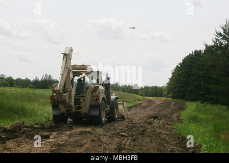 Ein Soldat mit Alpha Company, 766th Engineer Brigade Bataillon von Marseille, Illinois, verwendet eine hohe Mobilität Ingenieur Hydraulikbagger (HMEE) - einem Baggerlader entwickelt speziell für das US-Militär - eine Straße Juni 8, 2015 umzubauen, am Fort McCoy, Wis., die Arbeit ist Teil einer Truppe Projekt Straßen zu reparieren und Wanderwege auf Fort McCoy's South Post. Zahlreiche Soldaten aus der 766Th die HMEE, ein Sortierer verwendet, Muldenkipper, und mehrere andere Stücke von schwerem Gerät die Reparaturen abgeschlossen. Die 766Th ist ein Illinois National Guard Einheit, die im Rahmen der 33. Brigade Combat Team fällt und ist spezialisiert auf die Unterstützung von Stockfoto