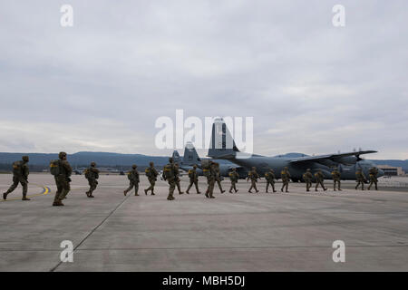 Us-Flieger und Soldaten in die 435Th Contingency Response Group, 4 Air Support Operations, 2 Air Support Operations Squadron, und der US-Armee Garnison Rheinland-Pfalz März in Richtung einer US Air Force C-130J Super Hercules auf der Flightline in Ramstein Air Base, Deutschland, 29. März 2018 zugeordnet. Die fallschirmjäger flog zu erwerben oder behalten Zertifizierungen zu springen. Stockfoto