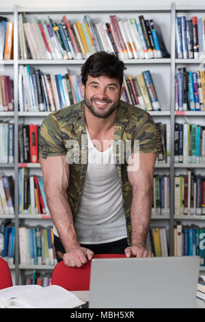Athletic Fitness männliche Kursteilnehmer mit Büchern Arbeiten in einer High School Bibliothek Stockfoto