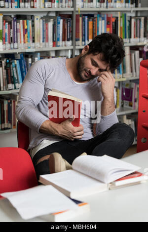 Junger Mann Student gelangweilt fühlen, während versucht wird, das Studium Eintrag Untersuchungen auf eine Universität oder Hochschule Stockfoto