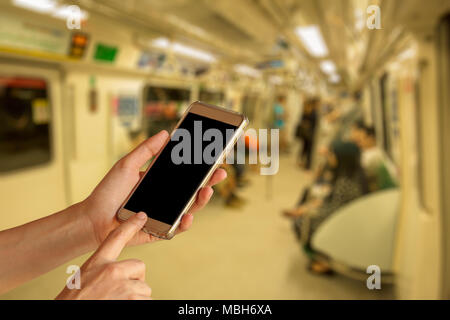 Frau Hand halten und Touchscreen Smartphone, Tablet, Handy über die Menschen in der U-Bahn blur Hintergrund Stockfoto