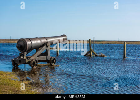 Gusseisen Schiff Kanone auf überschwemmten Küstenregion. Logo entfernt. Stockfoto