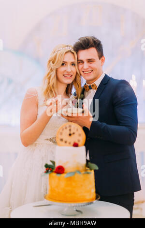 Hübscher Bräutigam seine schönen blonden Braut Fütterung mit Hochzeitstorte Stockfoto