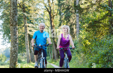 Glücklich und Active Senior paar Fahrrad draußen im Park Stockfoto