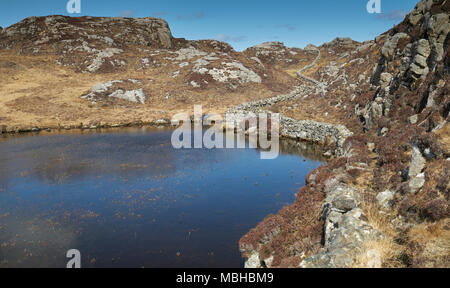 Ungewöhnliche Mauer aus Stein gebaut aus Granit Felsen schlängelt sich durch die felsige Landschaft von Uig auf der Isle of Lewis in Schottland. Stockfoto