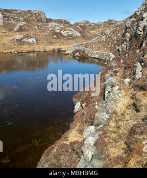 Ungewöhnliche Mauer aus Stein gebaut aus Granit Felsen schlängelt sich durch die felsige Landschaft von Uig auf der Isle of Lewis in Schottland. Stockfoto