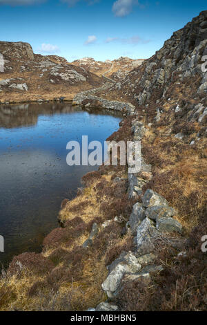 Ungewöhnliche Mauer aus Stein gebaut aus Granit Felsen schlängelt sich durch die felsige Landschaft von Uig auf der Isle of Lewis in Schottland. Stockfoto