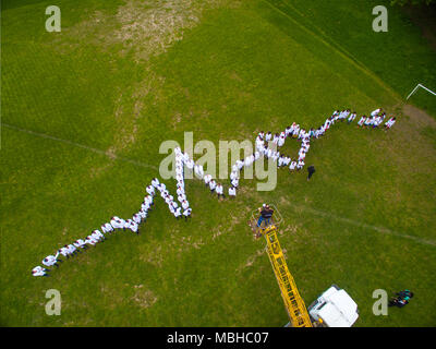 Ternopil, Ukraine - 22. April 2018: Medizinstudenten Stehend auf dem Gras, live Herzen Chart. Verschiedene Nationalitäten. Physycians tragen weiße medical Uniform. Stockfoto