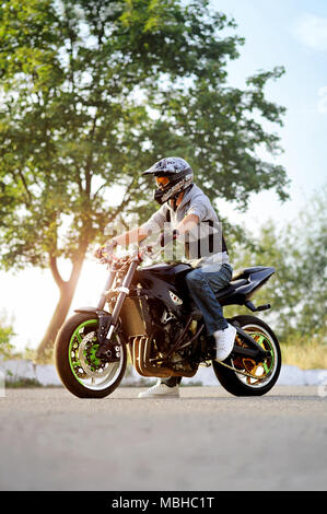 Ternopil, Ukraine - 28. August 2015: Junge männliche Biker sitzen auf dem Motorrad mit Sommer Stadt Straße. durch das Tragen von schützender helm. Eindrucksvoll und zuversichtlich. Stockfoto