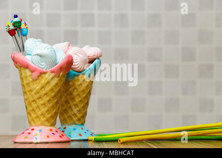 Blau und Rosa Meringue in den rosafarbenen und blauen Kegel mit Cupcakes, grünen und gelben Sticks auf Holz Tisch weißer Hintergrund Stockfoto