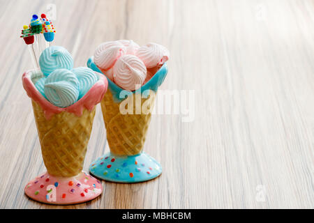 Blau und Rosa Meringue in den rosafarbenen und blauen Kegel mit Cupcakes auf Holz Hintergrund oder glückliche Mütter Tag Stockfoto