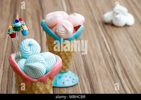 Blau und Rosa Meringue in den rosafarbenen und blauen Kegel mit Cupcakes auf Holz Hintergrund und weiße Baisers, glücklichen Muttertag Stockfoto