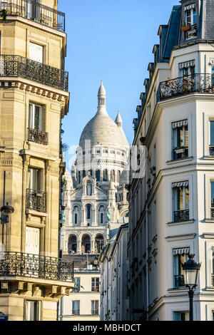 Die Basilika des Heiligen Herzen von Paris durch eine enge Straße zwischen typischen Gebäude mit einem Vintage Straße Licht im Vordergrund. Stockfoto