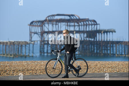 Brighton. 11. April 2018. UK Wetter: ein Radfahrer fährt vorbei Der marode West Pier in Brighton an einem schönen sonnigen Morgen entlang der Südküste mit der Wettervorhersage bis in Großbritannien in den nächsten Tagen Gutschrift zu warm: Simon Dack/Alamy leben Nachrichten Stockfoto