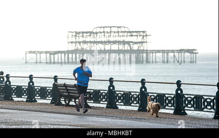 Brighton. 11. April 2018. UK Wetter: ein Läufer mit seinem Hund durch das verlassene West Pier von Brighton direkt am Meer an einem schönen sonnigen Morgen entlang der Südküste mit der Wettervorhersage bis in Großbritannien in den nächsten Tagen warm. Viele Läufer sind in der Ausbildung für den Brighton Marathon, der findet am kommenden Sonntag: Simon Dack/Alamy leben Nachrichten Stockfoto