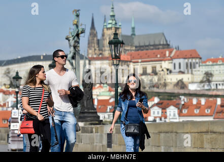 Prag, Tschechische Republik. 11 Apr, 2018. Touristen Spaziergang auf der Karlsbrücke in Prag, Tschechische Republik, am 11. April 2018. Auf dem Hintergrund ist die Prager Burg mit dem St.Veits Dom gesehen. Quelle: Vit Simanek/CTK Photo/Alamy leben Nachrichten Stockfoto