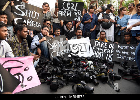 Kolkata, West Bengal, Indien. 11 Apr, 2018. Fotojournalisten gesehen sitzen um ihre Kameras halten Plakate während des Protestes. Hunderte von Journalisten protestieren gegen die herrschende Partei angeblichen Angriff auf Journalisten über Bengalen während Panchayat Nominierung Deckung. Die Rallye begann an der Mayo Straße Mahatma Gandhi Statue. und Dorina Kreuzung in Kalkutta gipfelte. Das Tragen von schwarzen Streifen auf Arme und für ihre Münder mit schwarzen Schals, Hunderte von Journalisten, Kameraleute und Fotojournalisten nahmen an der Kundgebung. Credit: ZUMA Press, Inc./Alamy leben Nachrichten Stockfoto