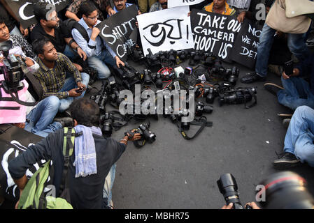 Kolkata, West Bengal, Indien. 11 Apr, 2018. Fotojournalisten gesehen sitzen um ihre Kameras halten Plakate während des Protestes. Hunderte von Journalisten protestieren gegen die herrschende Partei angeblichen Angriff auf Journalisten über Bengalen während Panchayat Nominierung Deckung. Die Rallye begann an der Mayo Straße Mahatma Gandhi Statue. und Dorina Kreuzung in Kalkutta gipfelte. Das Tragen von schwarzen Streifen auf Arme und für ihre Münder mit schwarzen Schals, Hunderte von Journalisten, Kameraleute und Fotojournalisten nahmen an der Kundgebung. Credit: ZUMA Press, Inc./Alamy leben Nachrichten Stockfoto