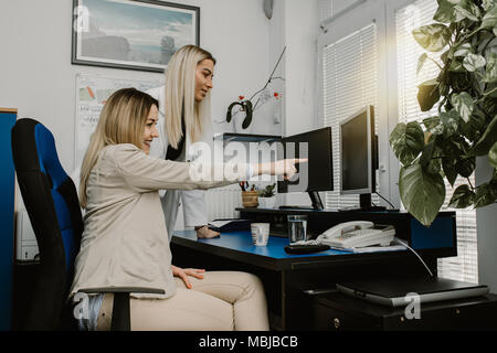 Zwei junge Kolleginnen zu diskutieren und die Arbeit an einem Projekt auf dem Computer Stockfoto