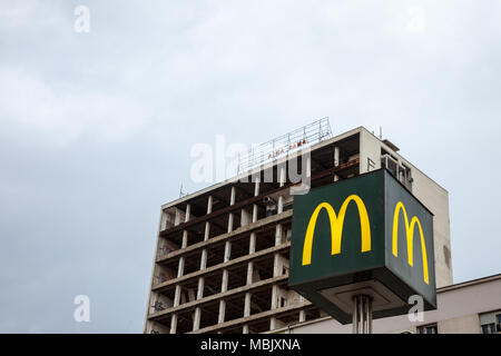 Belgrad, SERBIEN - 31. MÄRZ 2018: Mc Donald's Logo mit seinem Wahrzeichen M vor einem halben Gebäude in der Innenstadt von Belgrad Bild eines Mc Dona zerstört Stockfoto