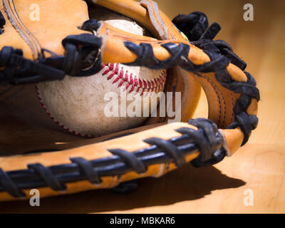 Close up Sport Hintergrund Bild eines alten verwitterten Leder Baseball mit Red Laces innerhalb eines Baseball Handschuh oder mitt mit komplizierten Details Stockfoto