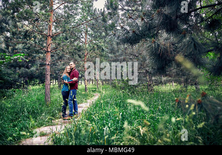 Junge hipster Paar in kariertem Hemd umarmen im Pinienwald. Liebe in der Natur. Stockfoto